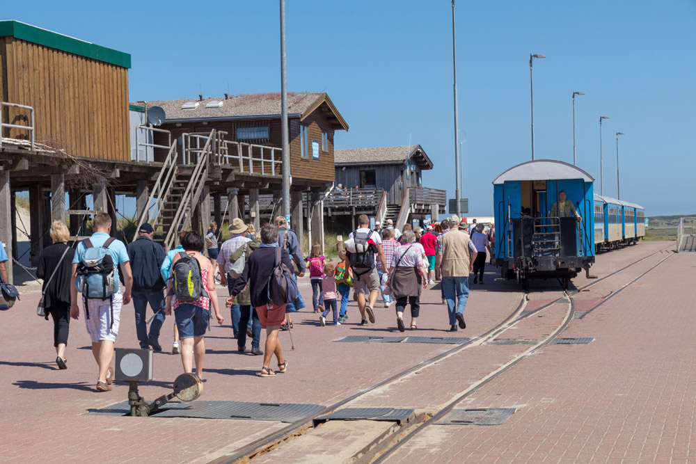Passagiere laufen im Hafen Wangerooge vom Schiff zur Inselbahn